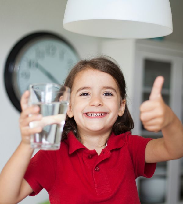 Kid holding a glass of clean water and giving a thumbs up